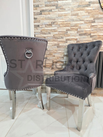 Two gray upholstered chairs with metal legs in a room with a stone wall.