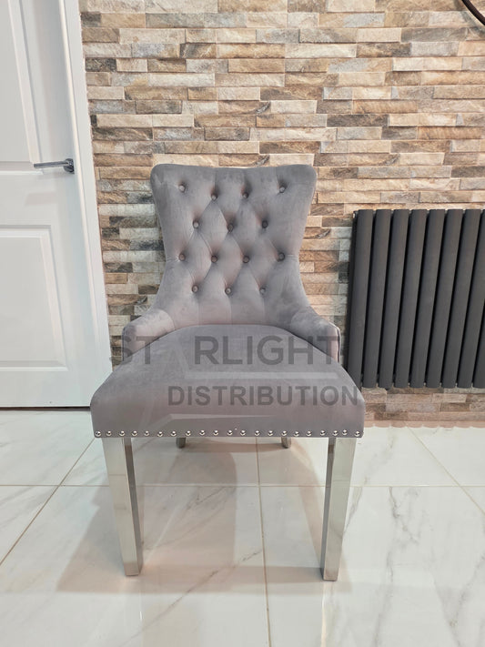 Gray tufted chair with metal legs against a brick-patterned wall.