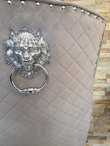 Gray quilted dining chair with a decorative silver lion head 